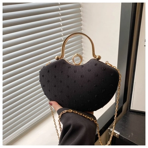 Detail of black heart-shaped handbag with textured fabric and golden ring clasp