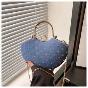 Close-up of heart-shaped denim bag featuring gold metal handle and rhinestone clasp