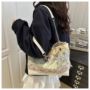 Detail of canvas bag with star print, frayed edges and metal chain strap on model
