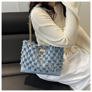 Detail of blue denim checkered tote with gold deer charm and fringe texture