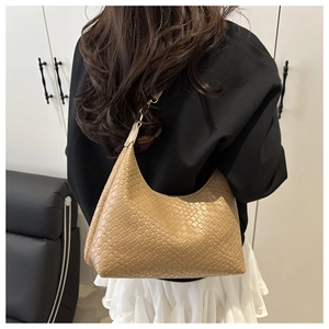 Detail of woven texture on a khaki crescent shoulder bag styled with elegant outfit