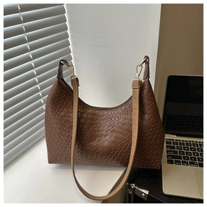 Macro detail of the woven texture and golden hardware on this dark brown hobo bag