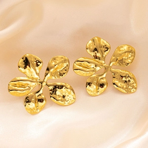 Detailed view of gold flower earrings with hammer finish on luxury satin fabric