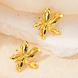 Close-up of gold flower butterfly earrings with polished finish on a stone surface
