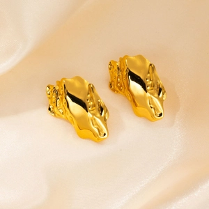 Macro shot of gold molten metal earrings on ivory silk, showing irregular liquid texture