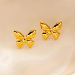 Detailed view of gold butterfly stud earrings on premium champagne silk fabric texture