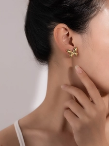 Close-up of a stylish gold butterfly stud earring worn by a model for a chic party look