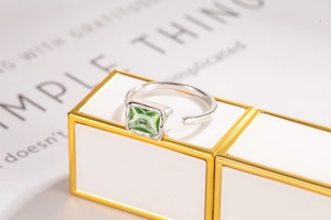 Detail of square green zircon set on adjustable silver band on a white pedestal