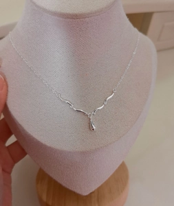 Detailed view of silver teardrop pendant necklace on a beige velvet jewelry display stand