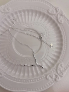 Detail of S925 sterling silver water drop pendant necklace on a decorative porcelain plate