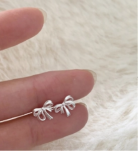 Vue macro de boucles d'oreilles nœud argentées délicates montrant taille et détails