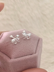 Vue macro détaillée de boucles d'oreilles nœuds en argent sur une boîte en velours rose
