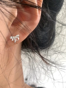 Gros plan d'une boucle d'oreille nœud en argent délicat portée pour un style minimaliste