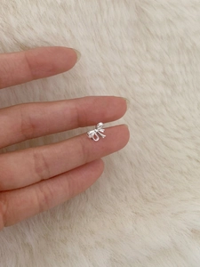 Vue macro d'une petite boucle d'oreille nœud en argent sur le bout d'un doigt