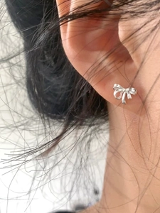 Gros plan d'une puce d'oreille en argent avec un nœud papillon au design minimaliste