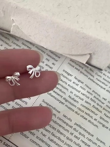 Gros plan de boucles d'oreilles nœud délicates en argent avec fermoir à vis sécurisé