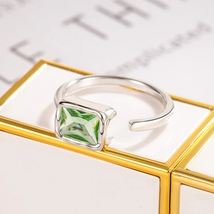 Minimalist silver ring with rectangular green zircon stone on a white display stand