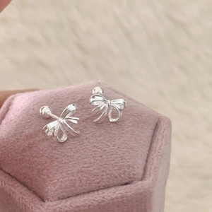 Boucles d'oreilles nœud ruban en argent sur une boîte à bijoux en velours rose