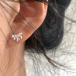 Élégante boucle d'oreille nœud en argent vue de côté en gros plan sur l'oreille