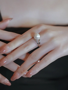 Close-up of a silver pearl ring on a finger featuring a double-forked hollow band design