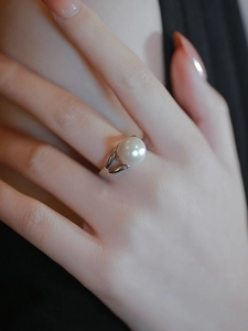 Detailed view of an elegant pearl ring with a crossover band worn on a finger
