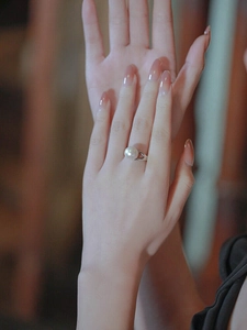 Close-up of elegant single pearl ring on model hand with silver split-shank design