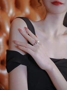 Detail of elegant pearl ring on model hand with silver intertwined band and high gloss