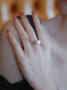 Detail of elegant pearl ring on finger featuring split silver band and white round pearl