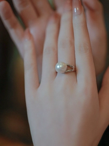 Close-up of elegant white pearl ring on finger featuring a silver adjustable band