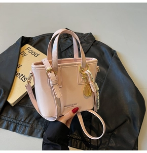 Detail of light pink bucket bag with gold tennis racket charm and brand lettering