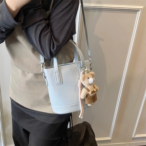 Light blue vintage bucket bag with a cute plush bear pendant and leather finish