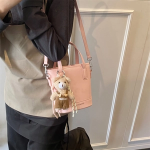 Pink fashion bucket bag with bear pendant and adjustable strap for women worn by model