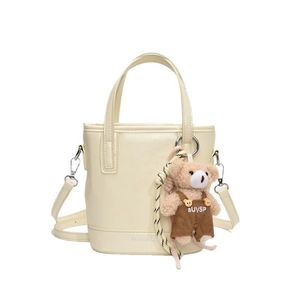 Elegant cream bucket bag with teddy bear charm and adjustable shoulder strap
