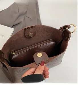 Detail view of large brown bucket bag interior featuring gold magnetic buckle and zipper pocket