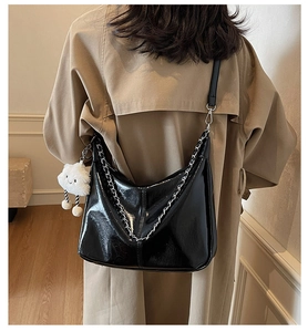 Close-up of black glossy patent leather tote with silver chain and white cloud charm