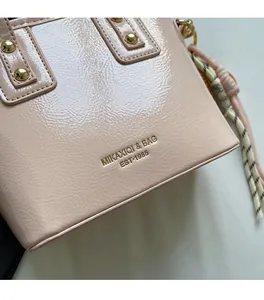 Detail of pink glossy leather bucket bag with gold rivets and striped tassel ornament