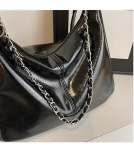 Detail of glossy black patent leather Hobo bag with silver metallic chain strap
