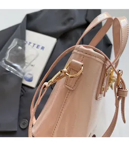 Close-up of pink glossy patent leather bucket bag with gold metal buckle and rivets