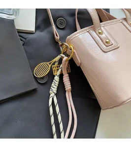 Detail of pink patent leather bucket bag with gold hardware and decorative charms