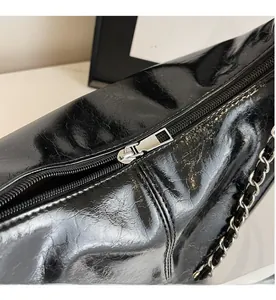Detail of smooth metal zipper and glossy black leather texture on stylish tote bag