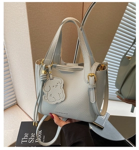 Close-up of light blue pebble leather bucket bag with puppy charm and gold hardware