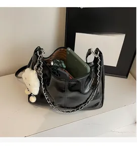 Spacious interior of a black patent leather tote bag with tablet and daily essentials