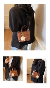 Detail of brown embossed bucket bag featuring playful doodles and plush sheep charm