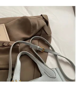 Detail of adjustable long shoulder strap and lychee grain leather on light blue bucket bag