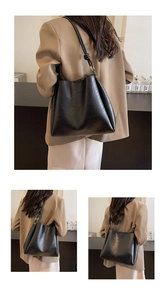 Detail of minimalist black bucket bag featuring textured faux leather and knotted shoulder strap