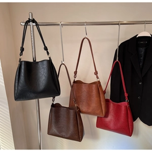 Showcase of minimalist bucket bags in black, dark coffee, caramel, and retro red colors