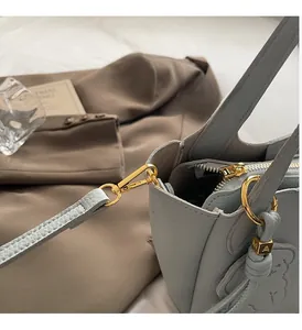 Macro shot of gold hardware and bear-shaped embossing on blue pebbled leather bucket bag