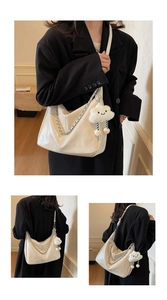 Detail of creamy white leather tote bag with silver metal chain and plush cloud charm