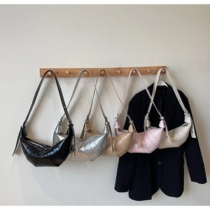 Detailed close-up showing five colors of quilted crescent shoulder bags on wooden wall hooks