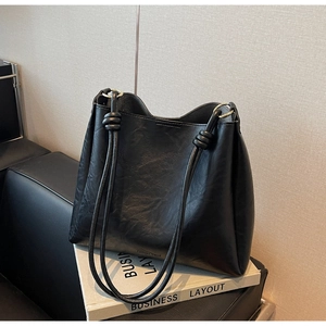 Detail view of black vintage tote bag with gold metal rings and knotted shoulder straps